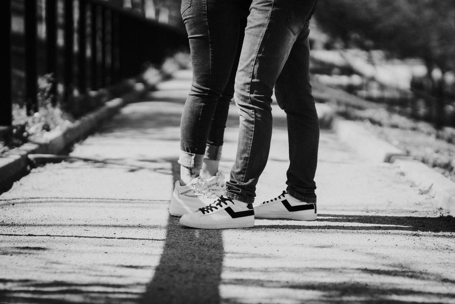 Black and white photo of feet close together on a wooden walkway.