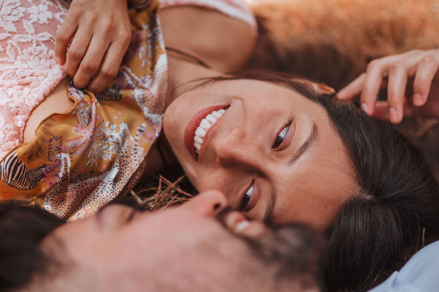 Intimate close-up shot of couple lying down outdoors with warm lighting.