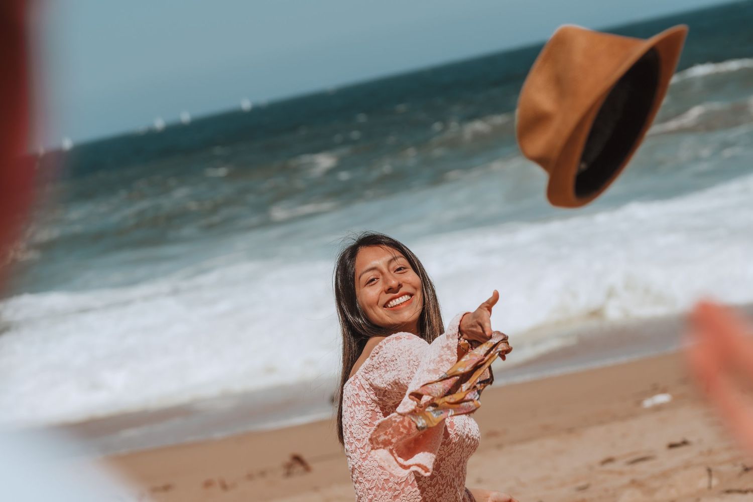 Two people having fun on sandy beach with waves crashing in background.