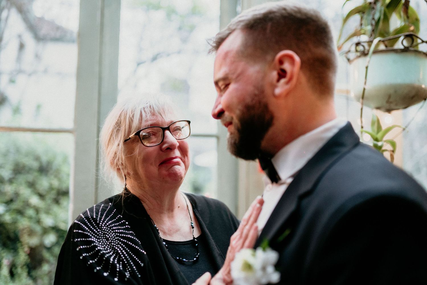 A loving couple share tender moments in multiple romantic black and white photos by a bright window.