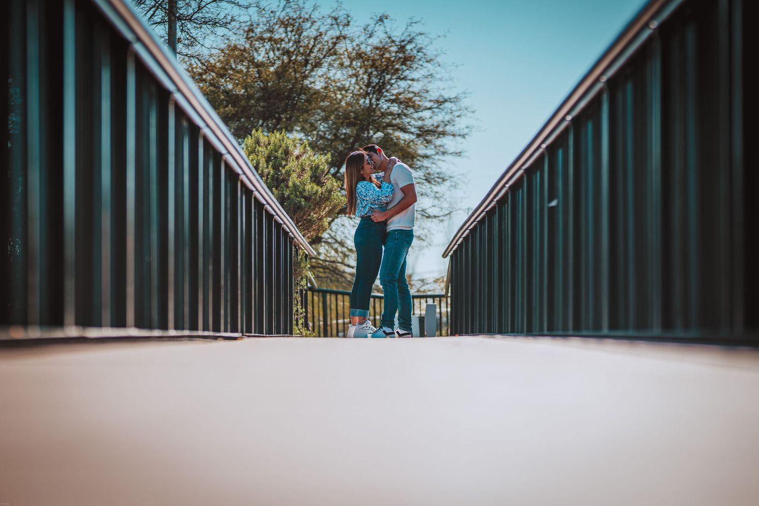 Symmetrical bridge photography with a couple embracing in the center distance.