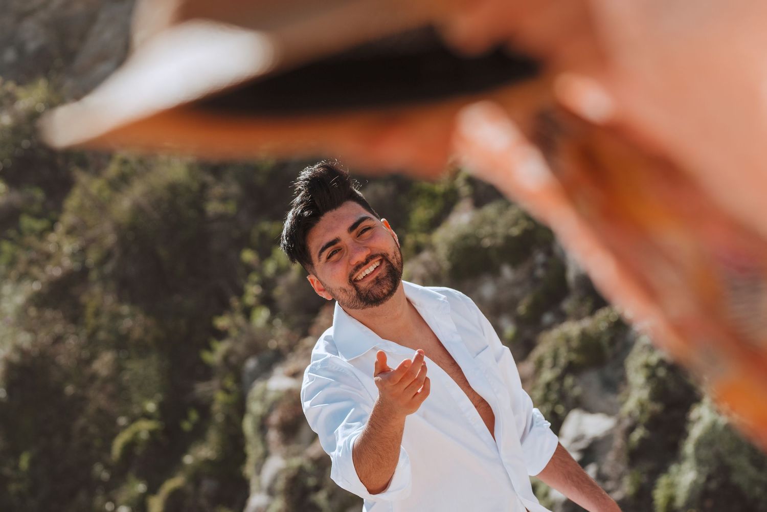 Person playfully posing outdoors on sunny day with natural backdrop.