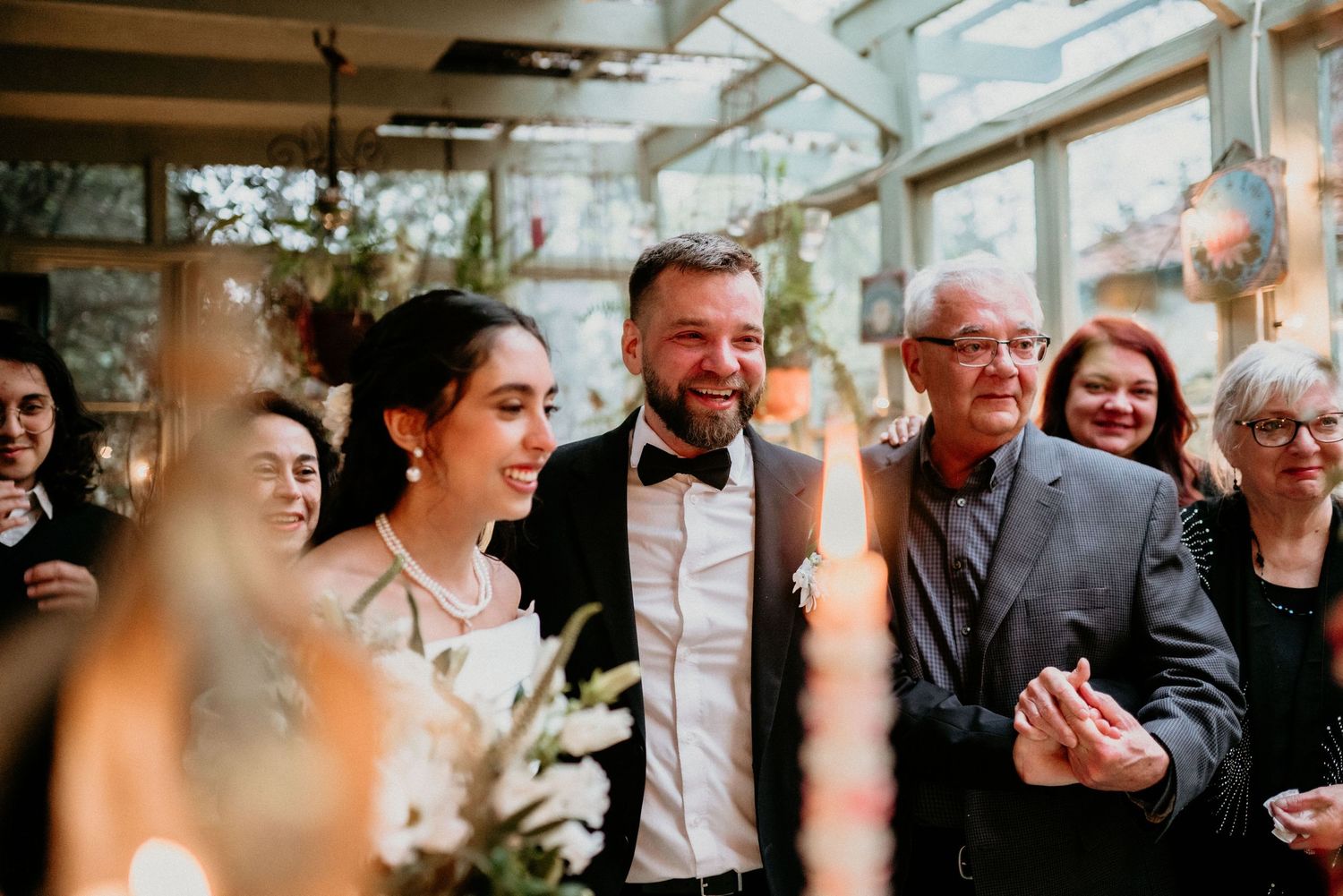 A joyful celebration at a wedding ceremony with smiles and laughter in a bright indoor venue with natural lighting and flowers.