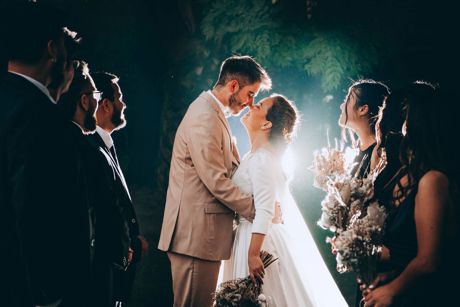 Dramatic backlit wedding ceremony scene with elegant decor and atmospheric lighting.