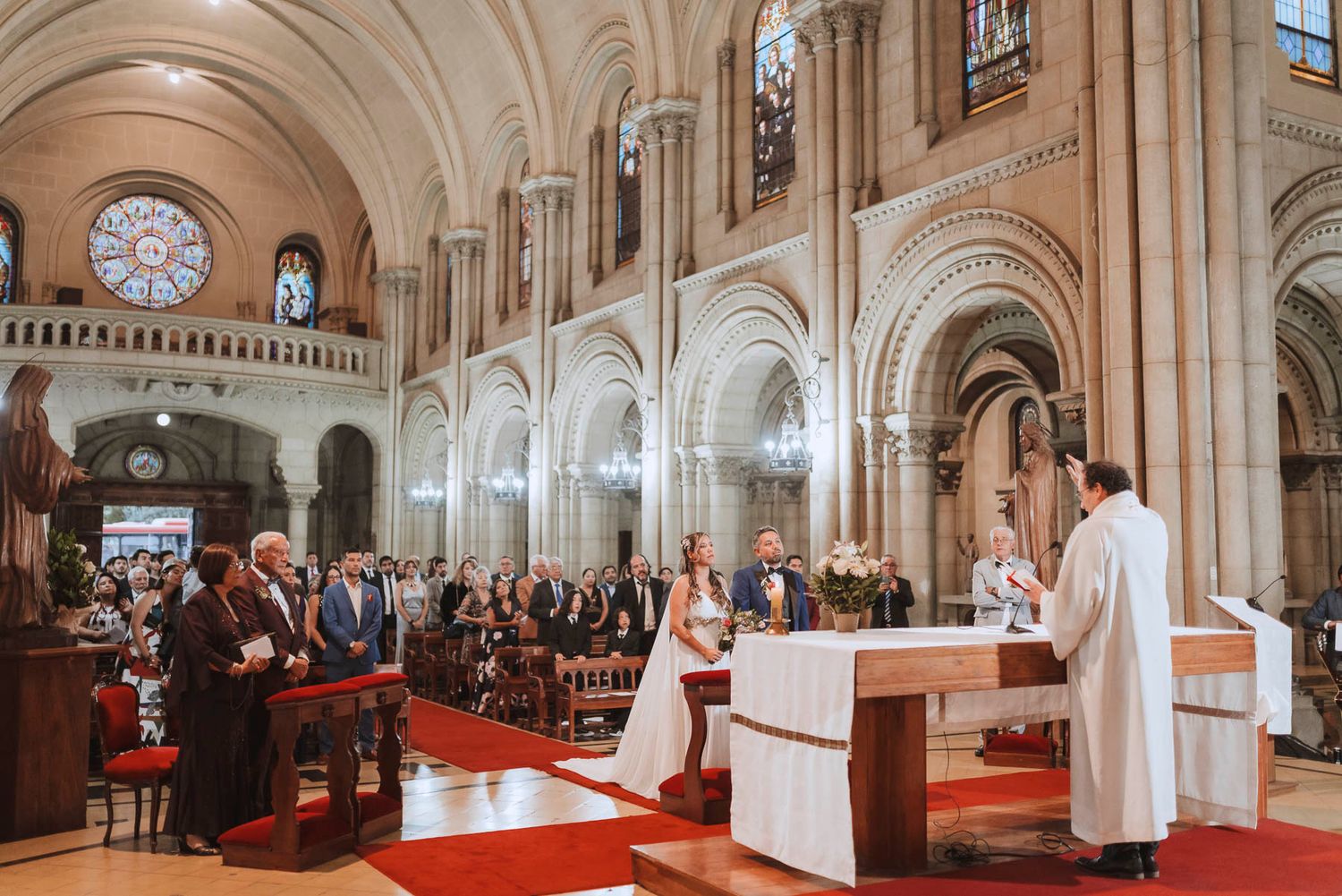 Cathedral wedding ceremony with vaulted arches and stained glass windows.