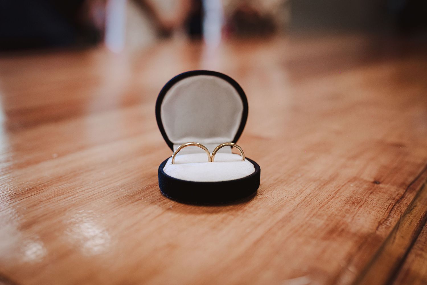 Several images showing an engagement ring in a box displayed on a wooden surface with dramatic lighting and shadows.