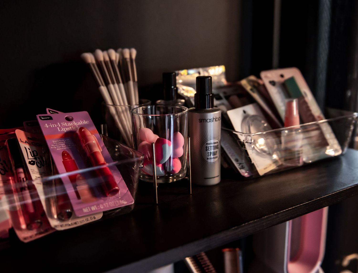 Illuminated bottles and glasses on a dark bar shelf create a moody atmosphere with red and purple lighting.