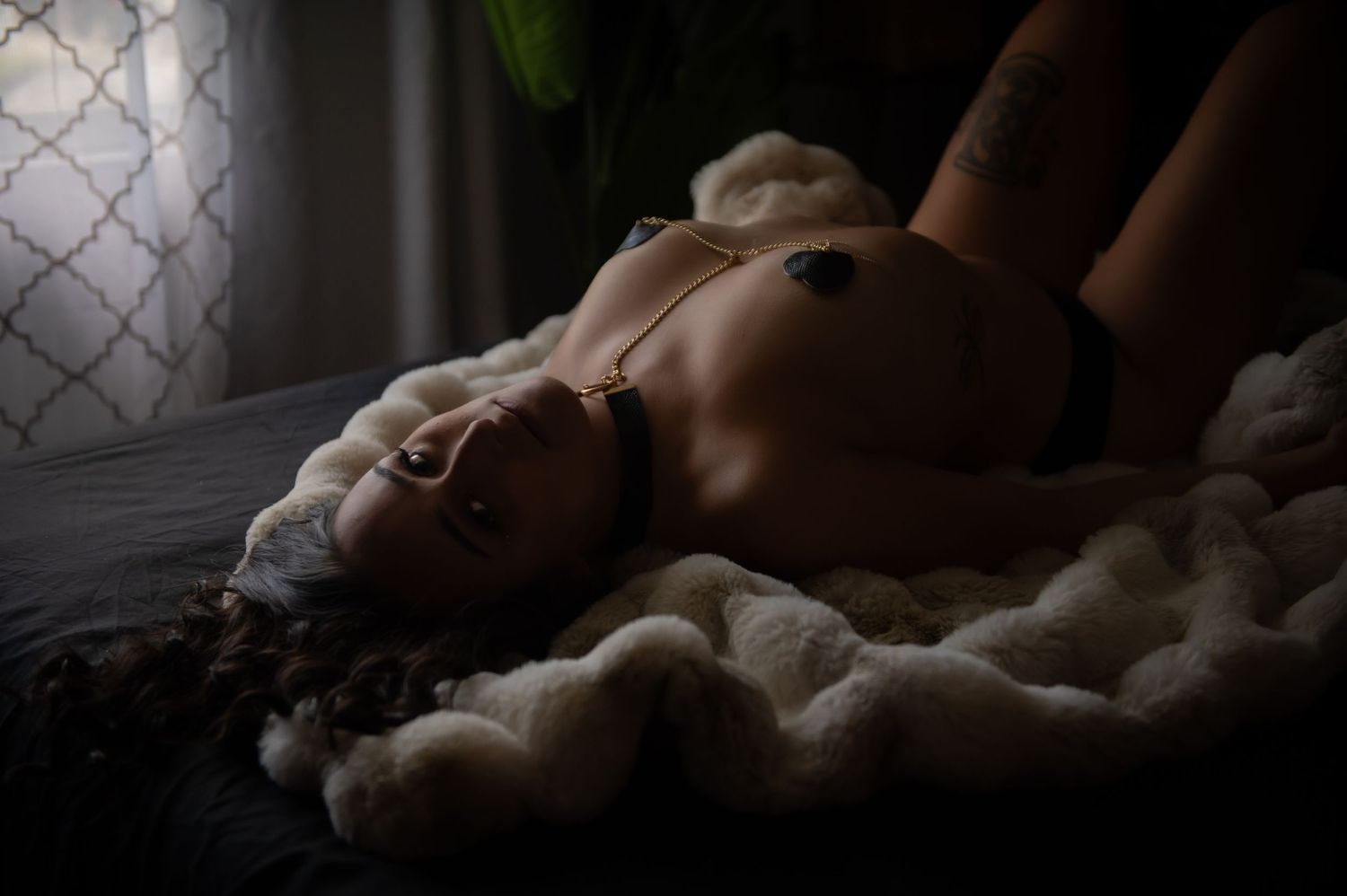 Intimate boudoir portrait on white bedding with soft natural lighting.
