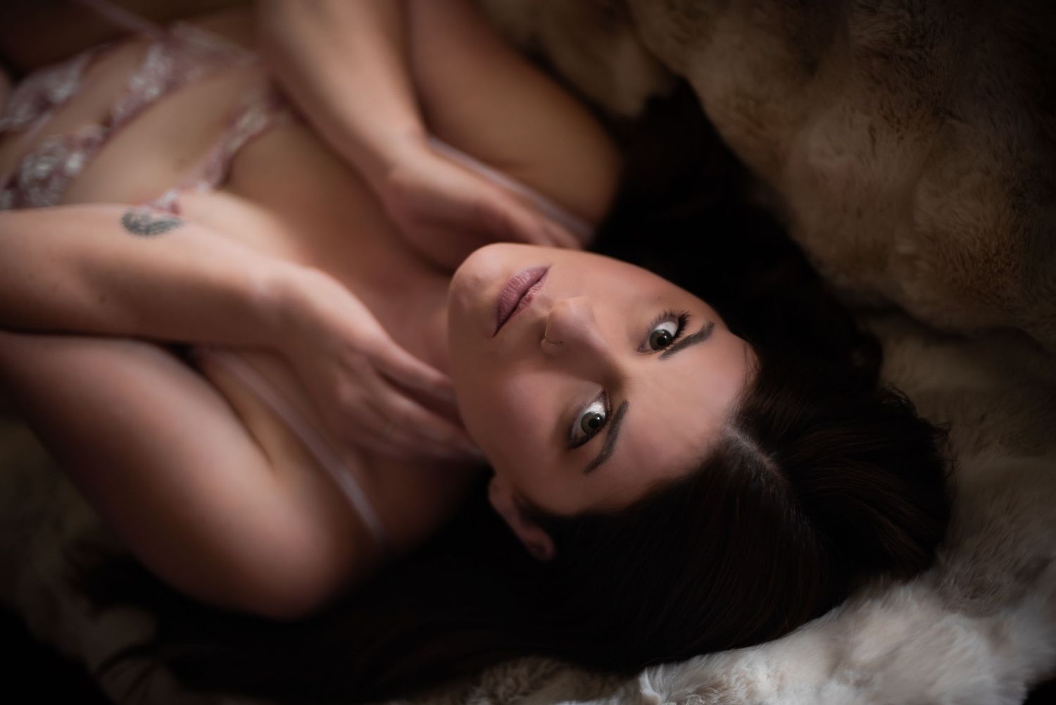 Artistic beauty portrait using dramatic lighting and intimate angles, with woman's hands framing her face.