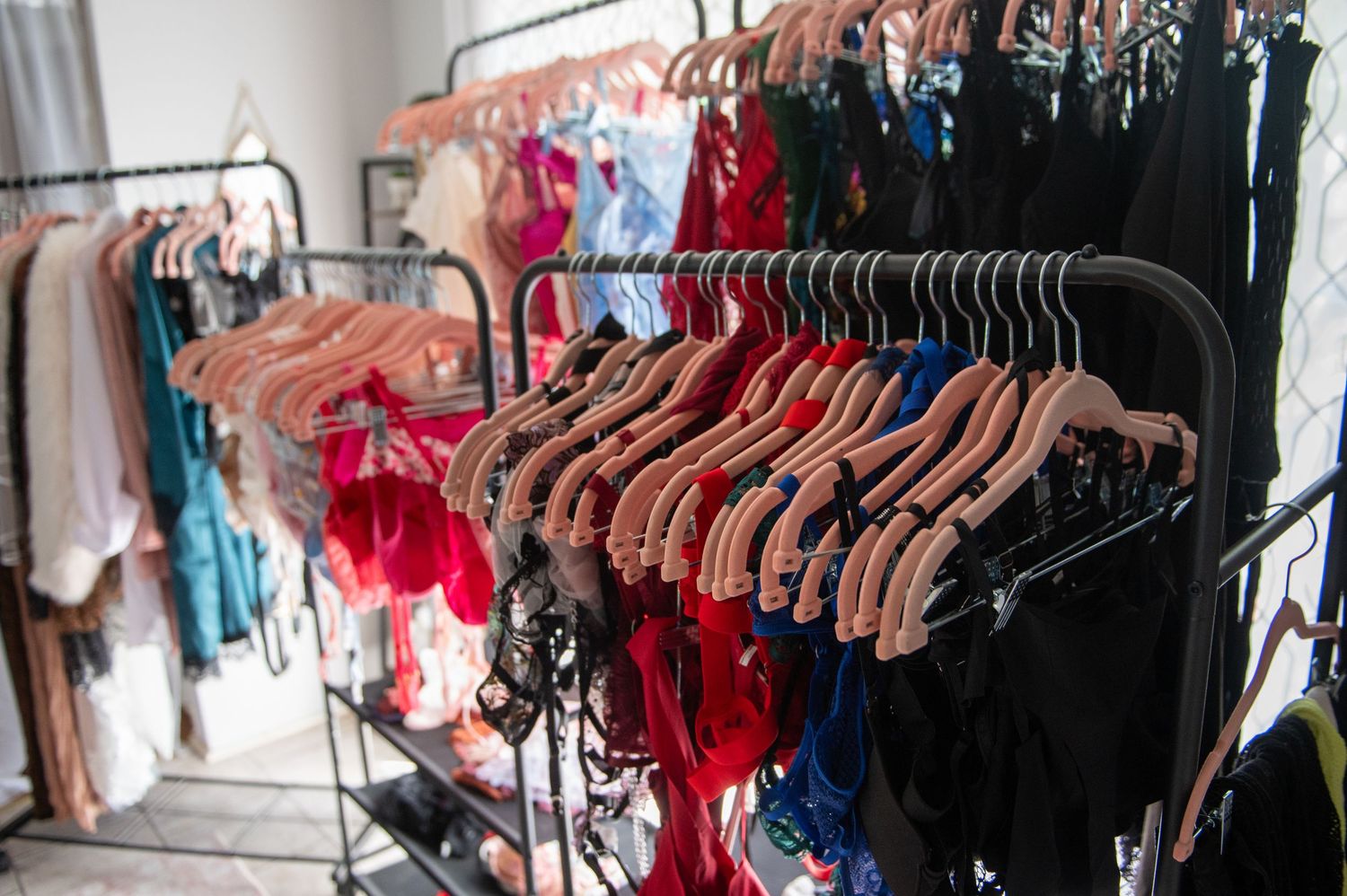 Racks of colorful lingerie and clothing on hangers displayed in boudoir client closet.
