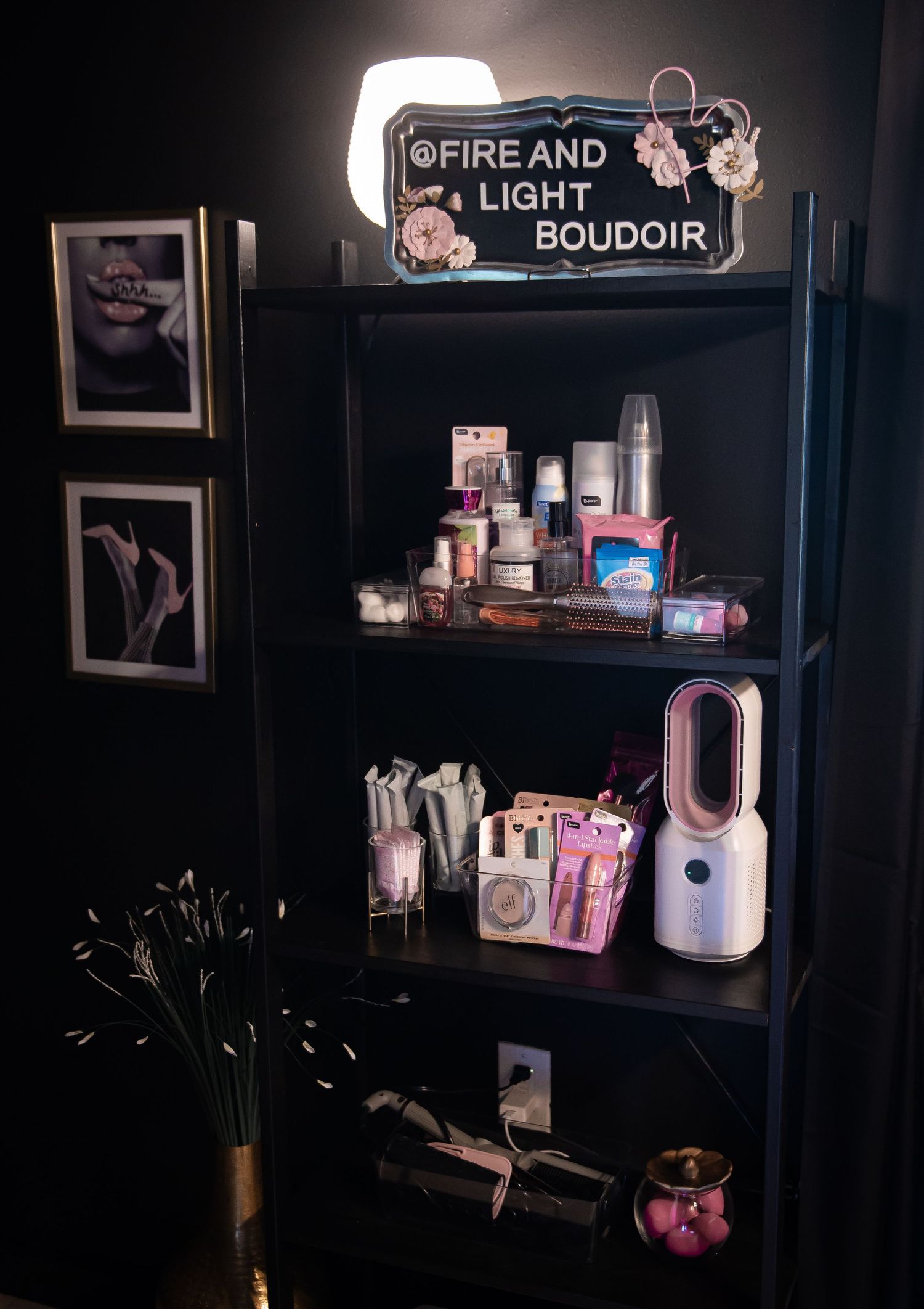 An organized beauty station in dark tones with ring light, shelving units, and beauty products arranged neatly ready for boudoir client use.