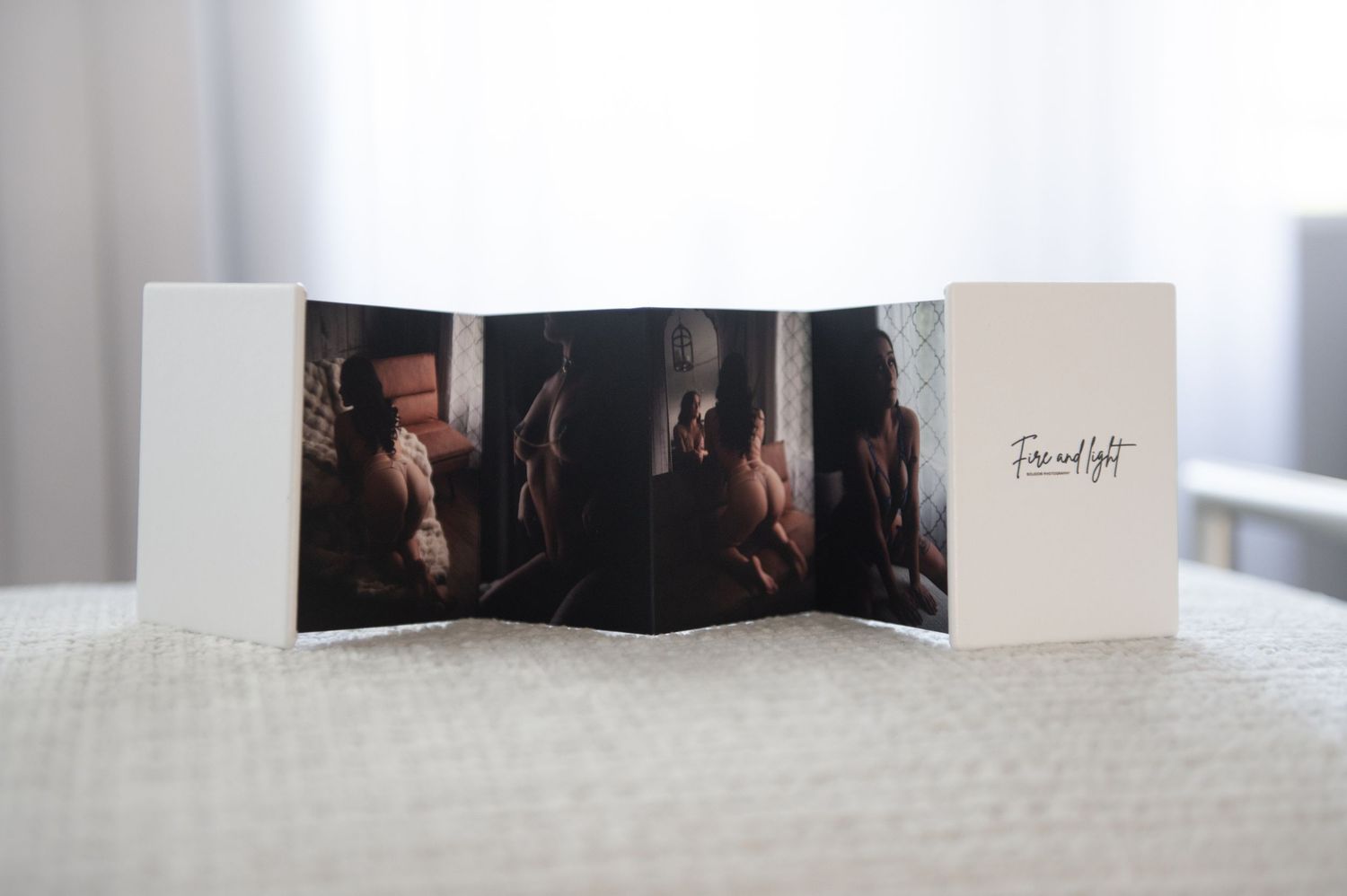 A folding photo display shows artistic bourdoir portrait photographs arranged in an accordion-style layout on a white surface.