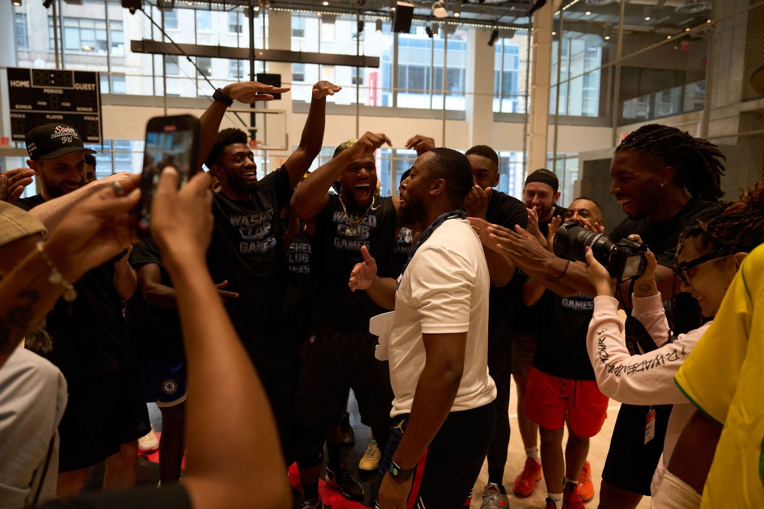 Crowd watching and cheering at an indoor sports event with hands raised in excitement.