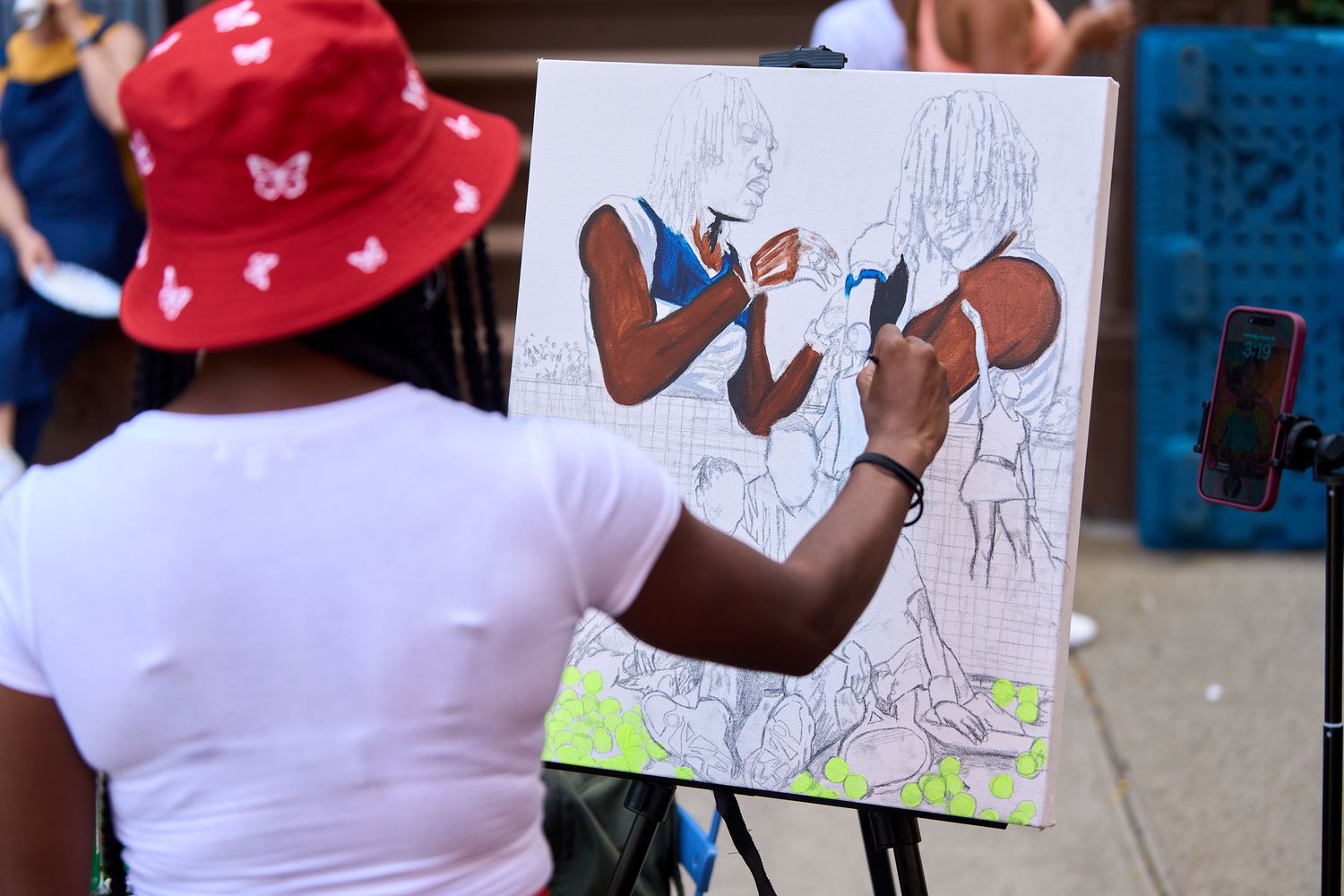 Students wearing red caps hold up drawings and artwork during an educational activity at school.