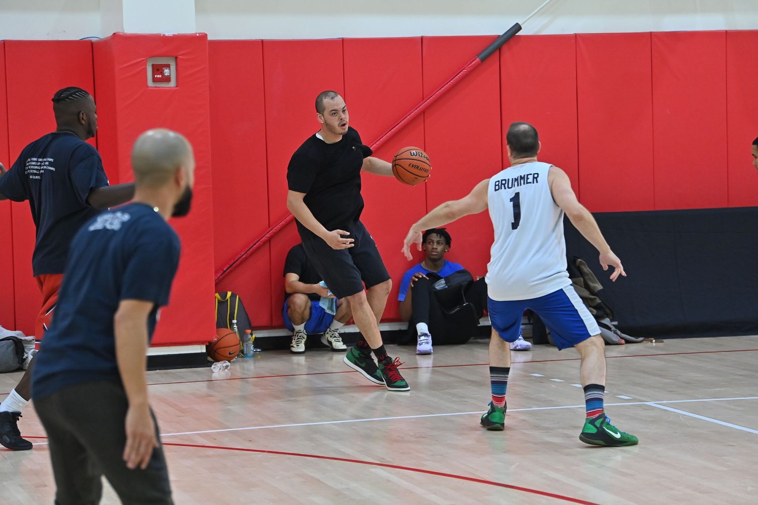 Basketball players practice drills and exercises on a red indoor court during a training session.