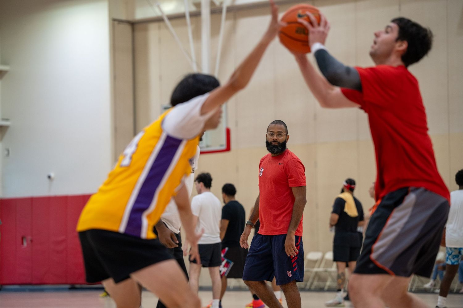 A group of players jump and dive for a basketball during an indoor recreational game.
