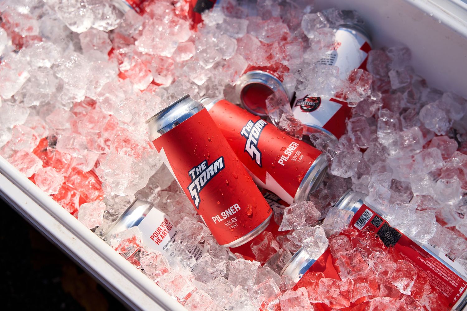 Red cans of Coca-Cola chilling in crushed ice at a beverage station.