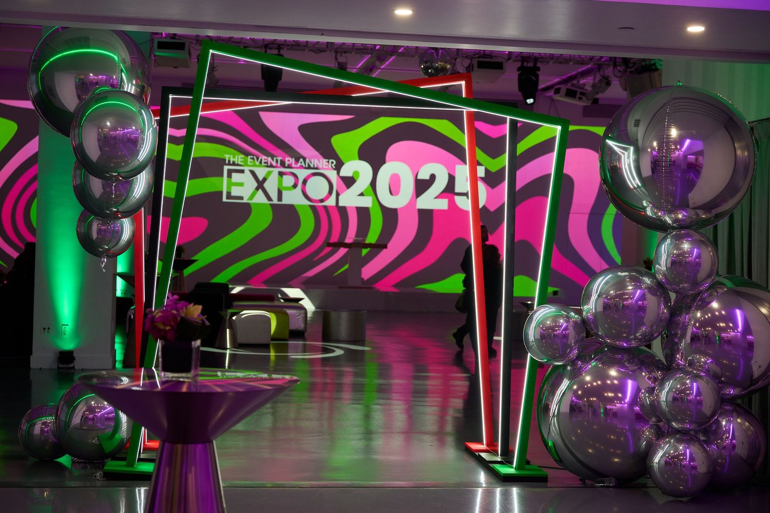 A nightclub interior with green and purple LED lighting features illuminated disco balls and modern geometric decor.