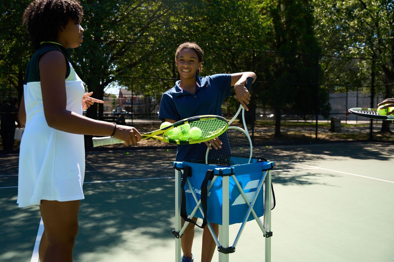 People enjoy outdoor activities and games at a sunny park with blue equipment and green trees.