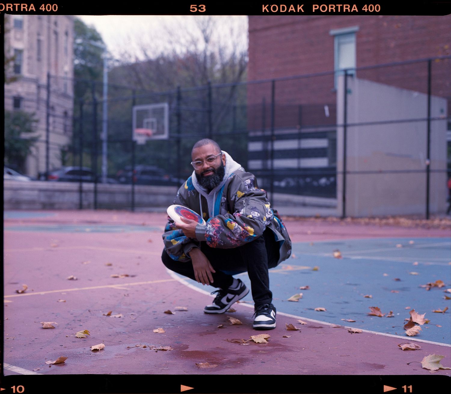 Film photo sequence showing someone in athletic shoes bending down to adjust or tie their shoelaces on a red court surface.