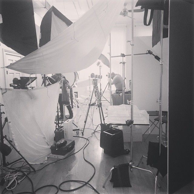 Behind-the-scenes studio photography setup showing lighting equipment, diffusion fabric, and camera gear in black and white.