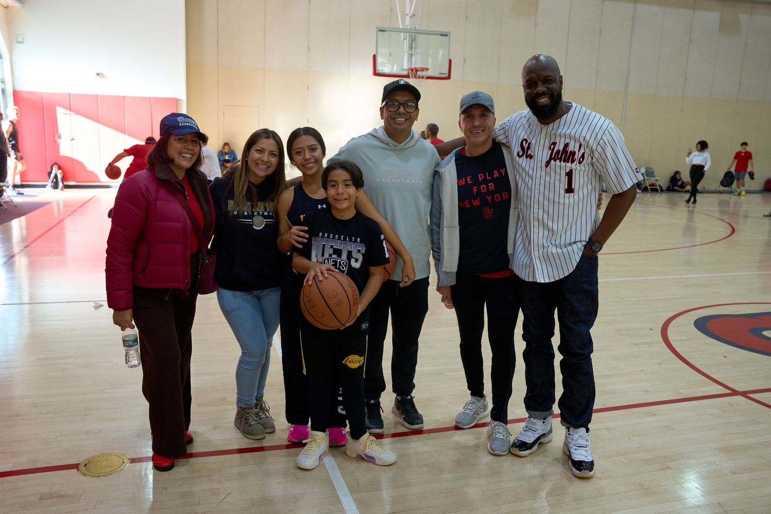 People gathered in a gymnasium with red and white walls for a basketball event.