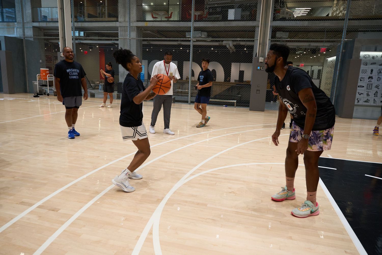 People playing volleyball in an indoor gymnasium during a recreational sports game.