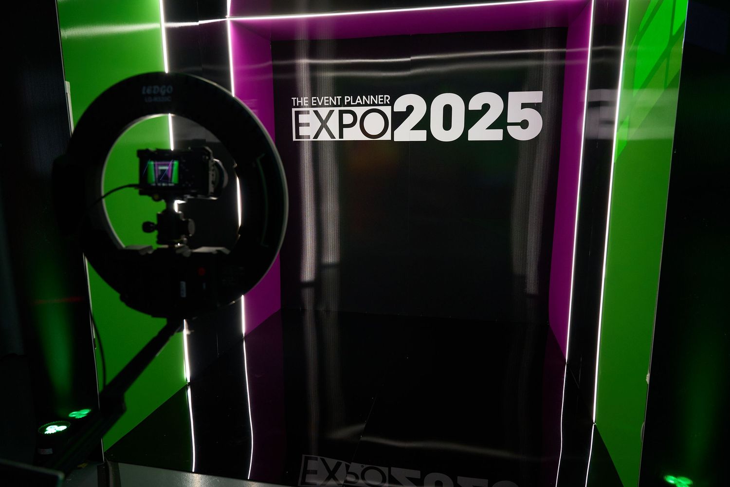 Illuminated green and pink neon signage displaying 'EXPO 2025' against a dark background.