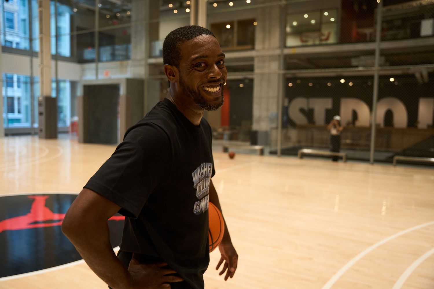 Basketball players practice defensive sliding drills on a shiny indoor court with reflective wooden floors.