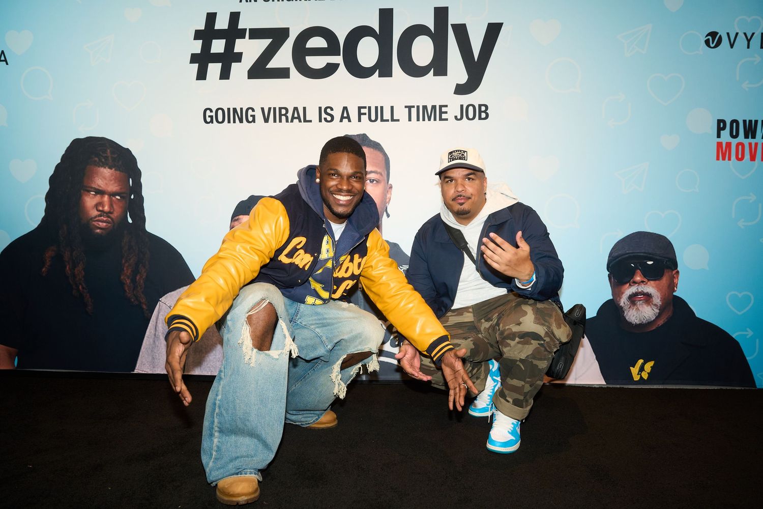Four men pose in front of a #zeddy promotional backdrop at a movie event.