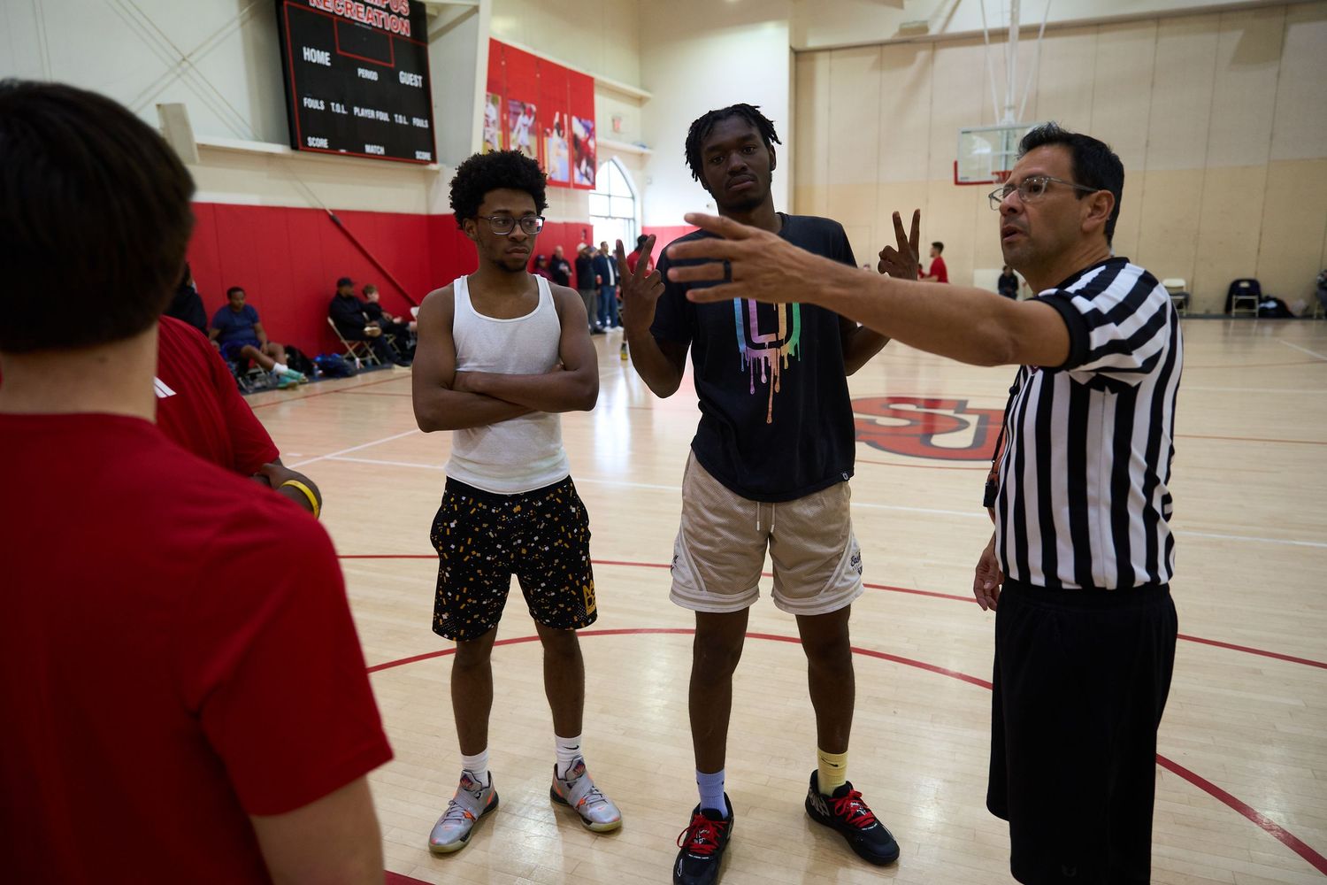 Basketball players and referee gathered on indoor court during game.