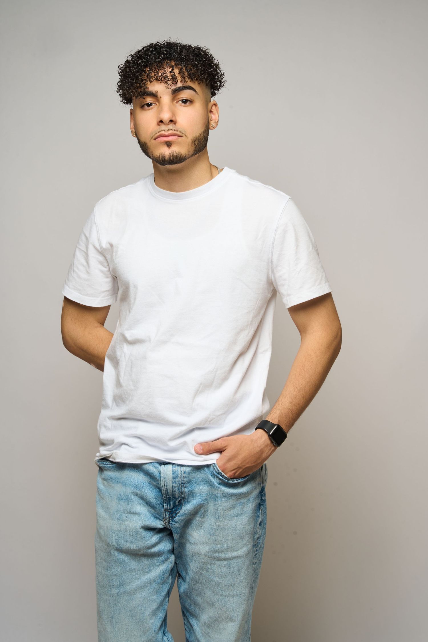 Person in casual attire with white t-shirt and light blue jeans poses against gray background.