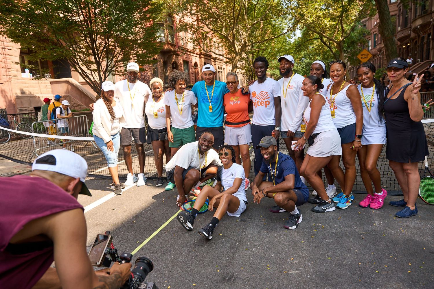 Large group of people lined up on a brownstone-lined street waiting in a queue.