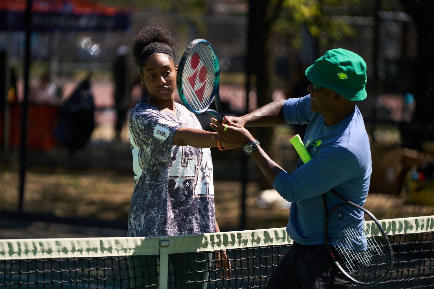 Tennis players engaged in an active training session on a sunny outdoor court.