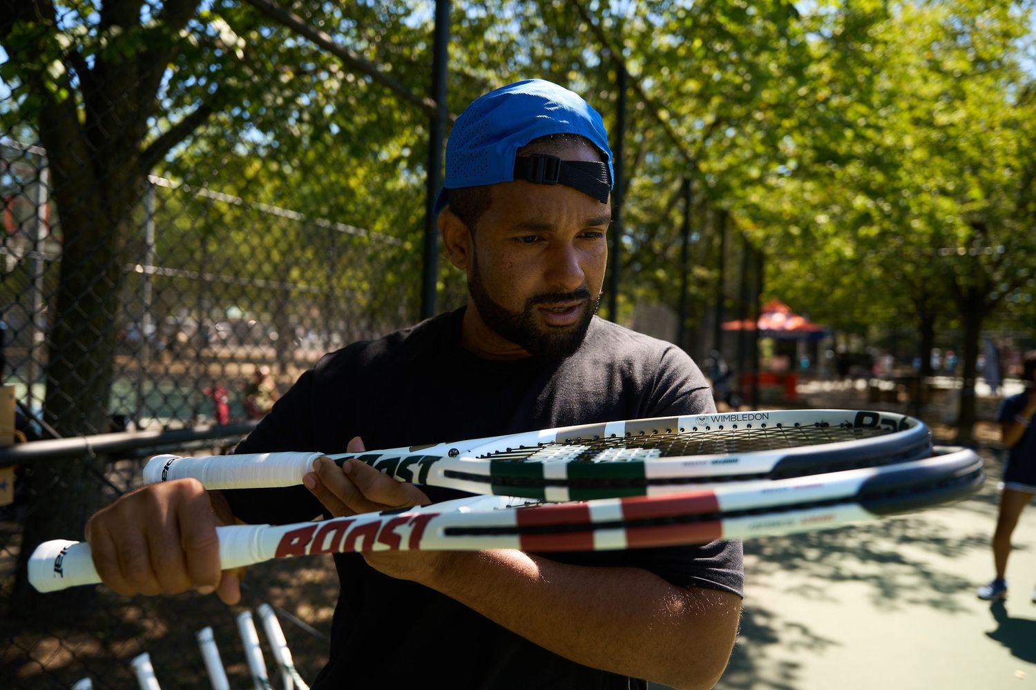 Tennis players practicing serves and volleys on an outdoor court during a sunny day.