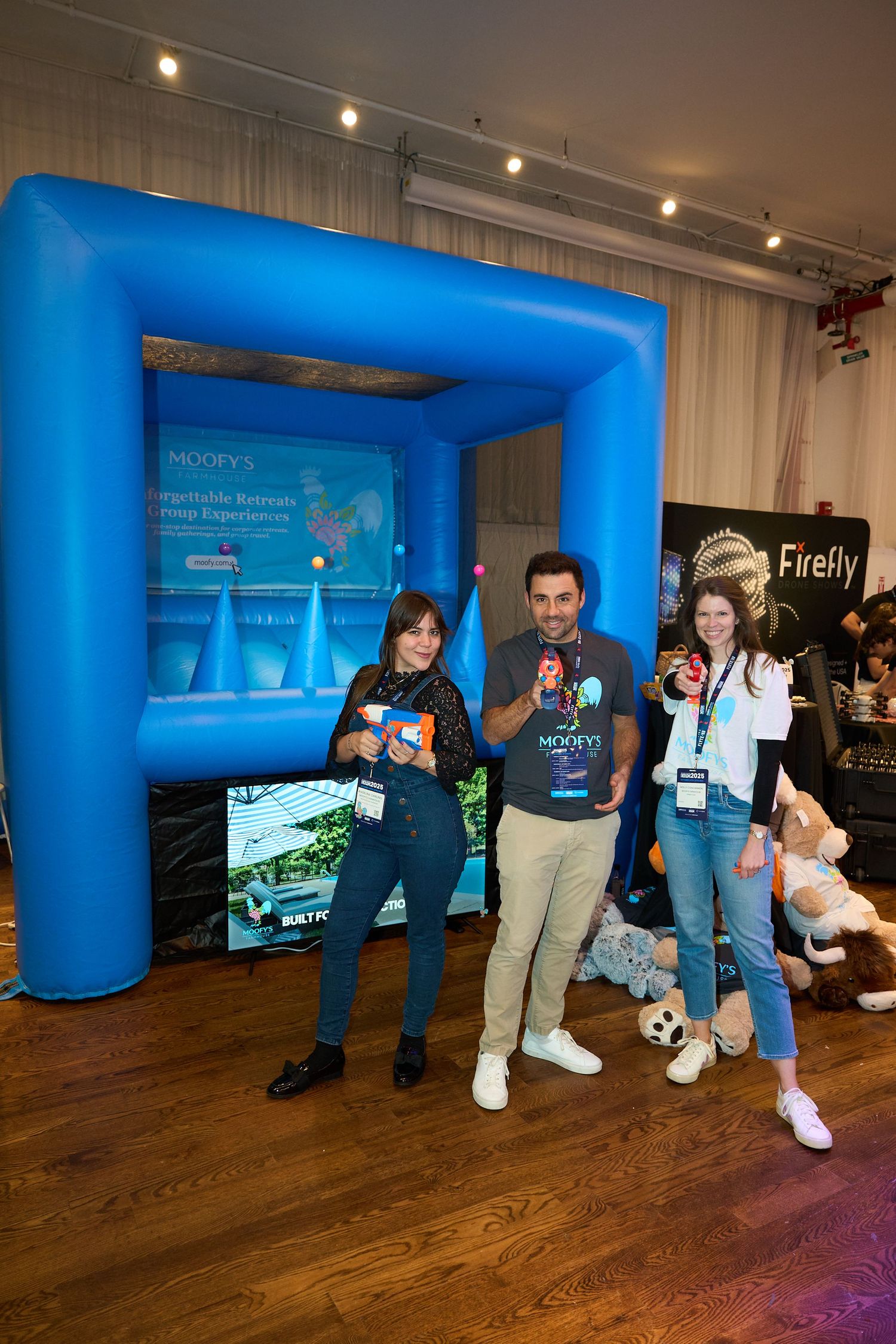 Event attendees pose in front of a bright blue inflatable photo backdrop at a corporate gathering.