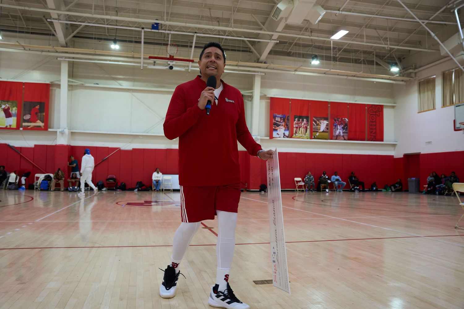 Wide angle view of indoor basketball court with red walls and wooden floors.
