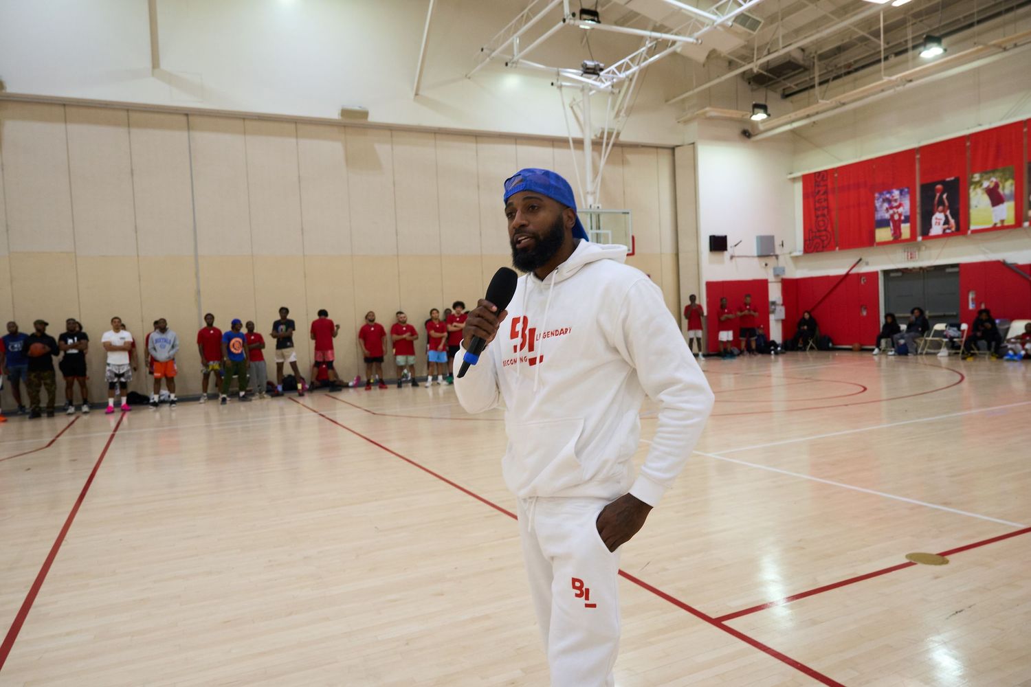 Wide view of a bright indoor gymnasium with red walls and white floor markings during an athletic event.