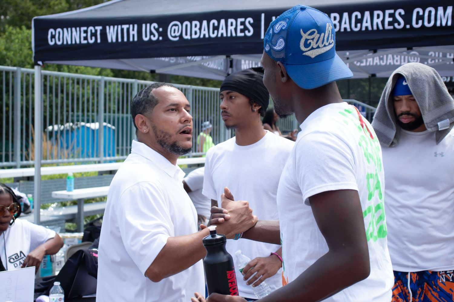 Group of people chatting and gathering at an outdoor community event with promotional banners.