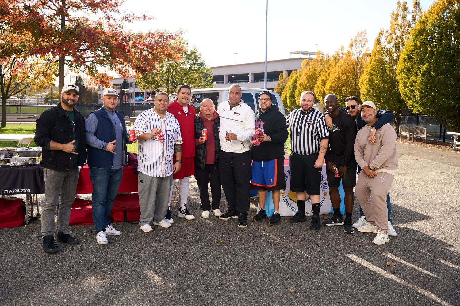 A group of people gathered outdoors in autumn with colorful fall trees in the background.