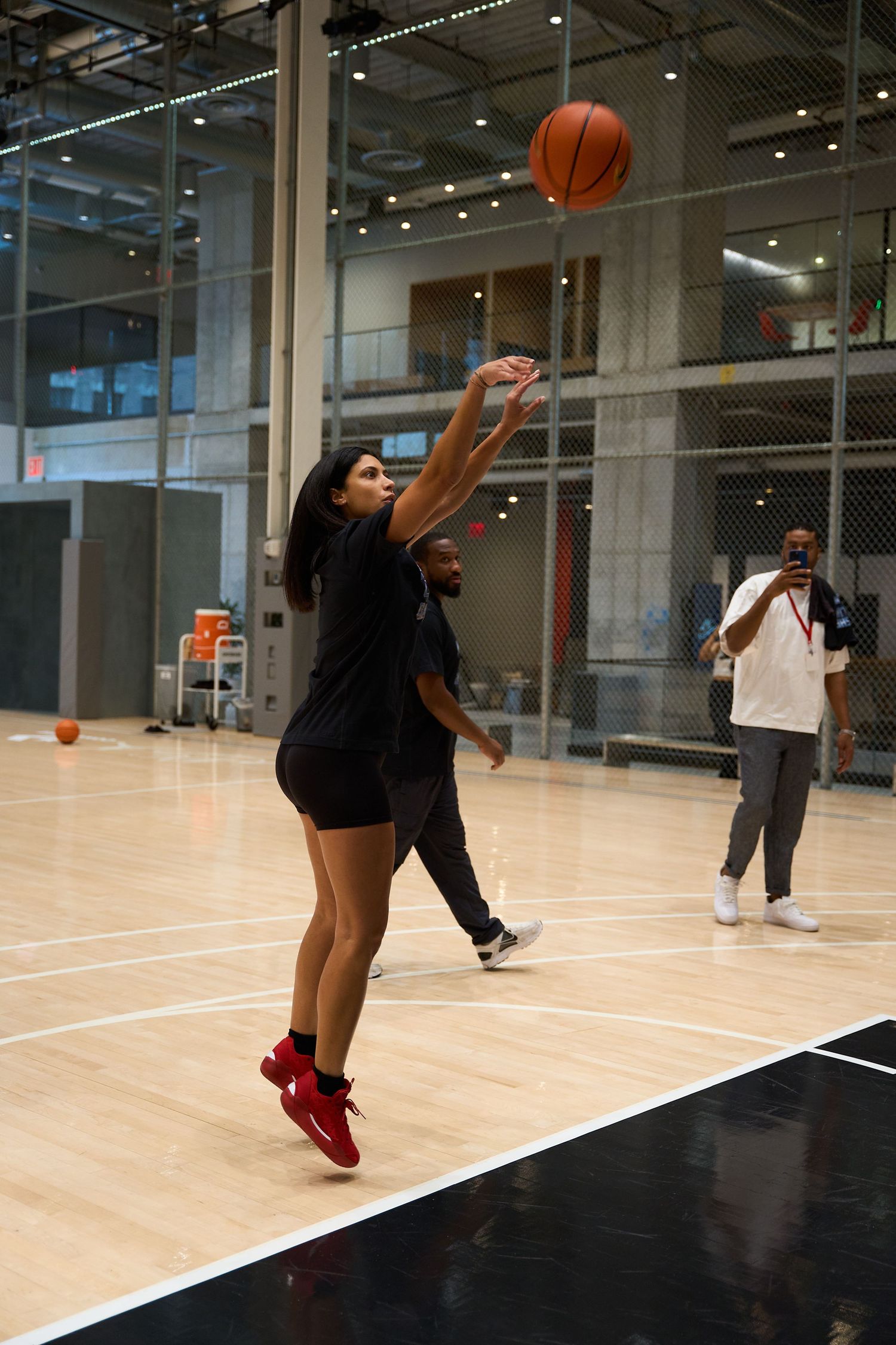 Basketball player in black athletic wear jumps to catch the ball during an indoor game at a recreational facility.