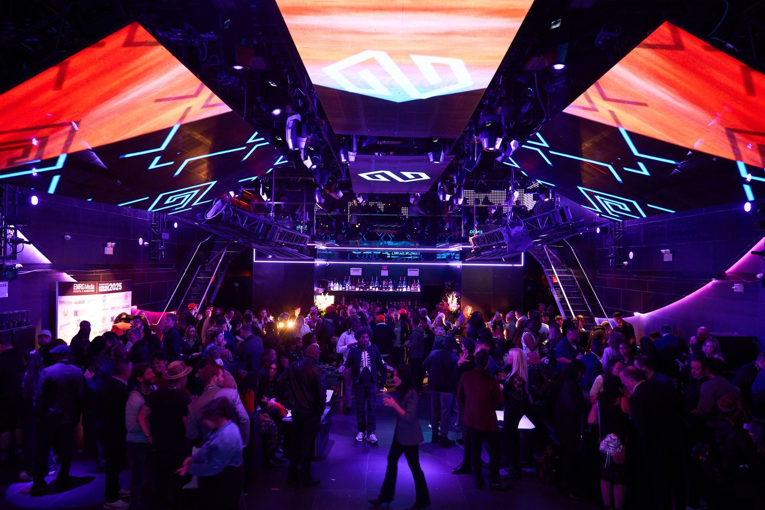 Large convention hall with dramatic red and blue lighting effects illuminating a crowded expo space.