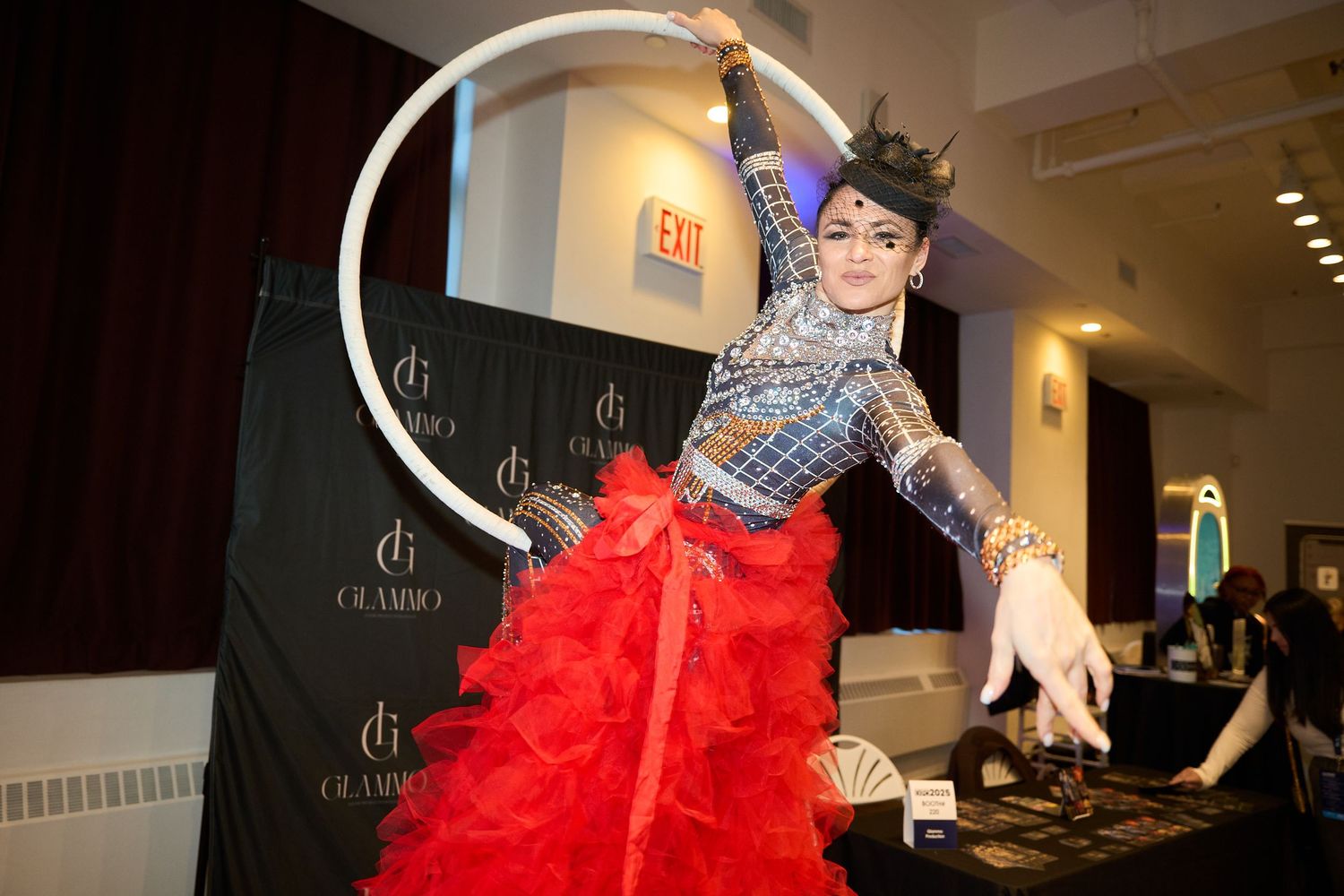 Performer in a red tulle skirt plays the harp during a theatrical performance.