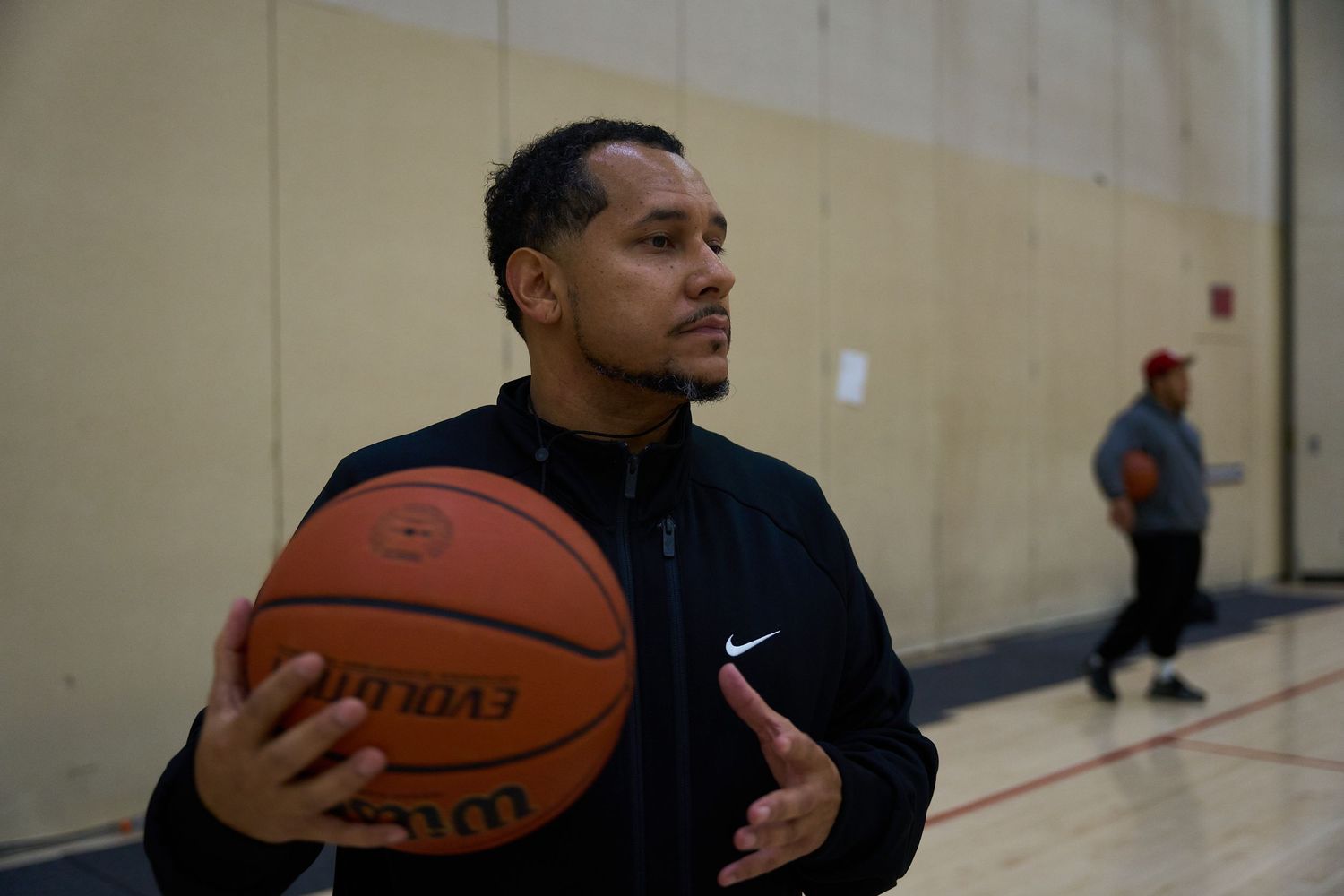 Referee holding a basketball in an indoor gymnasium setting.