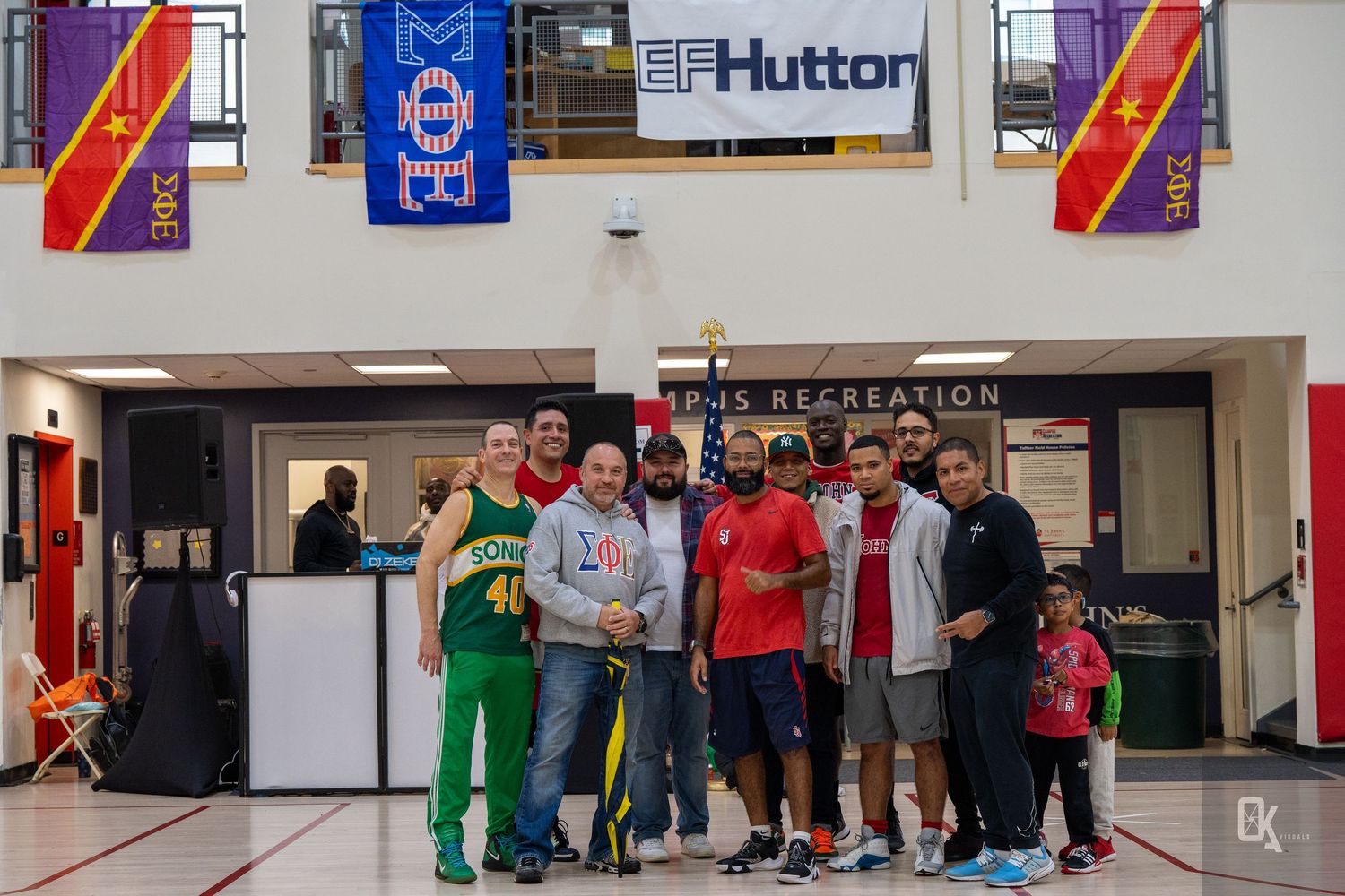 Students gather in a university recreation center hallway with sports banners and flags displayed on the walls.