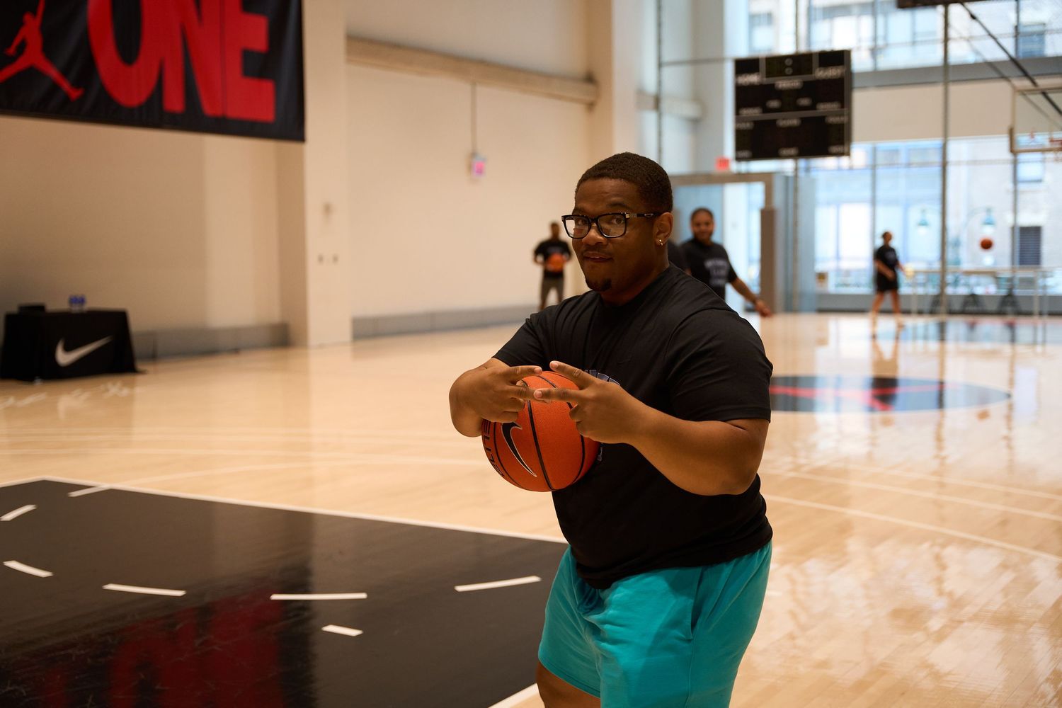 Basketball players practice drills on an indoor court wearing protective face masks during training.
