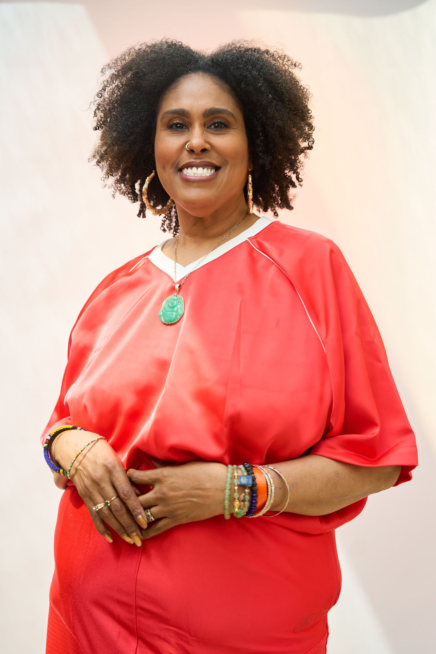 Woman in red outfit with colorful bracelets and turquoise pendant necklace smiling.