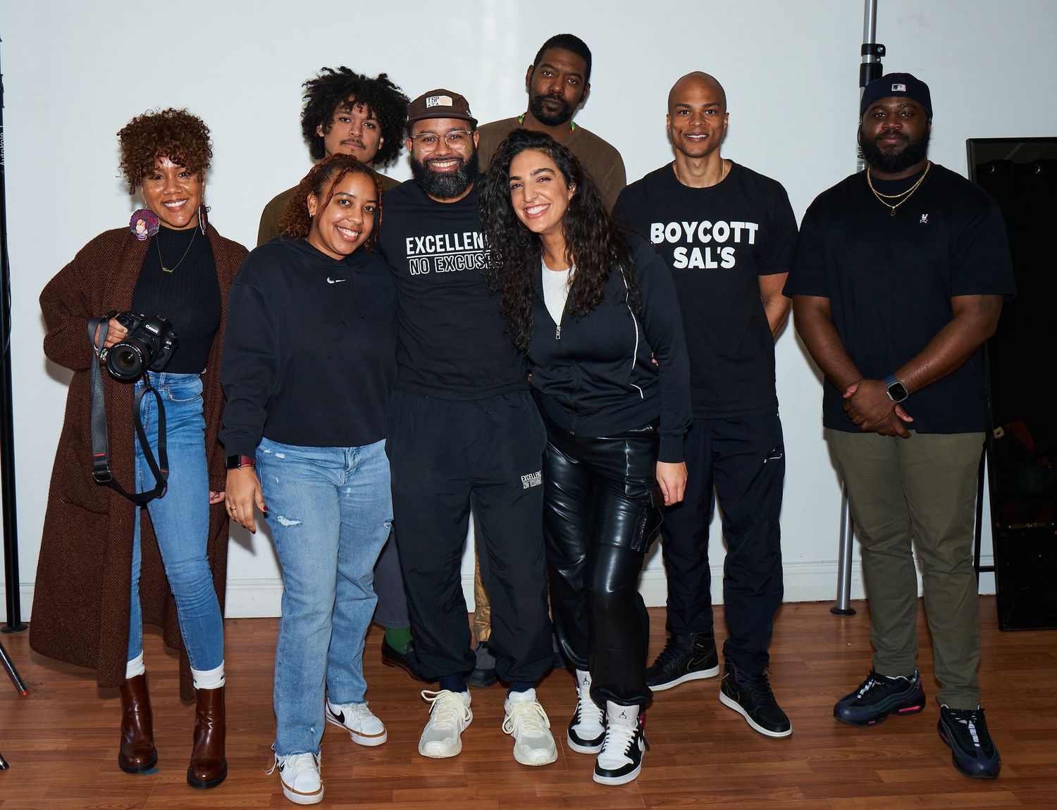Group of people wearing black shirts and casual clothing pose together for a casual indoor photo.