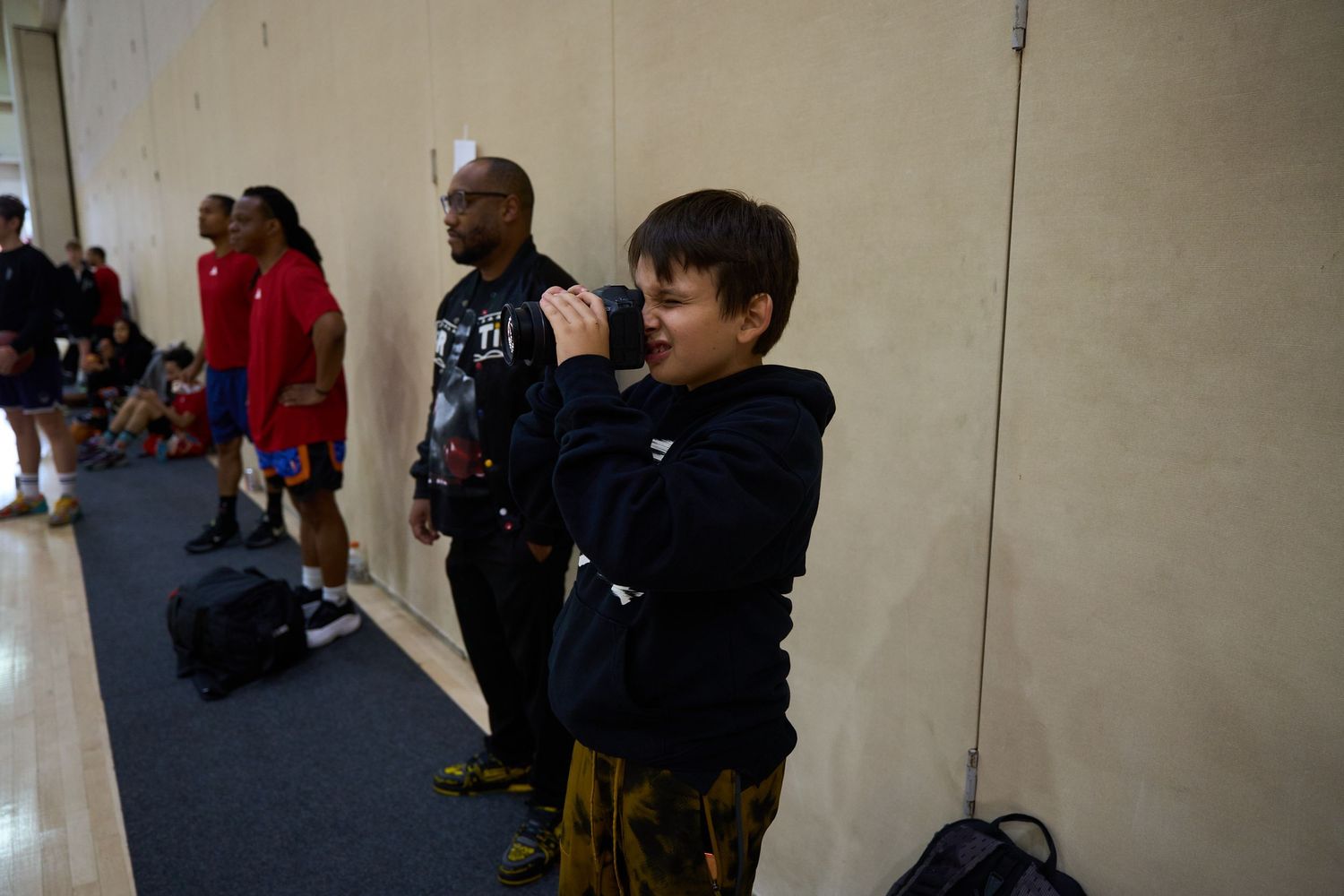 People watching and participating in activities along the wall of an indoor sports facility.