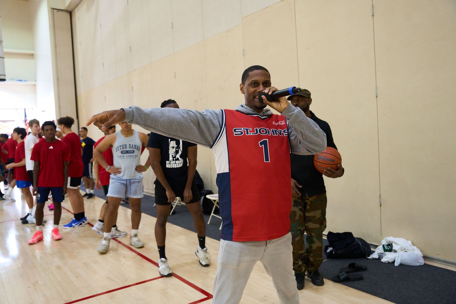 Players line up along the wall of a basketball court during practice drills.